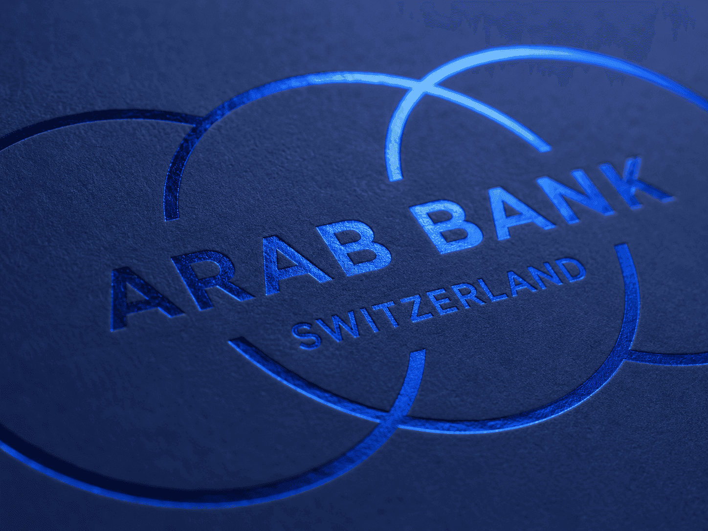 Le logo Arab Bank Switzerland marqué à chaud en bleu sur une couverture bleu nuit